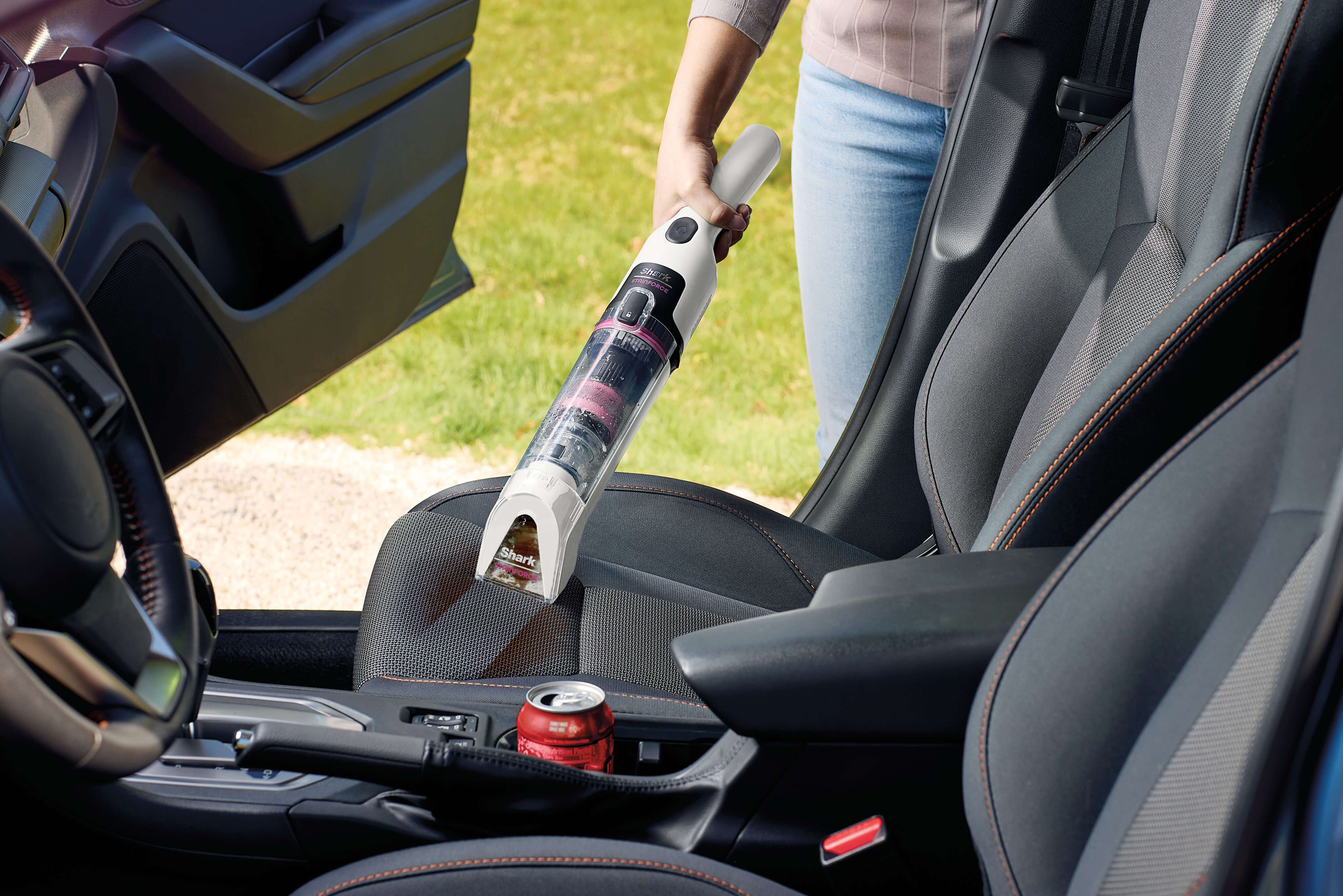 Person using a Shark StainForce handheld vacuum to clean motor oil spilled