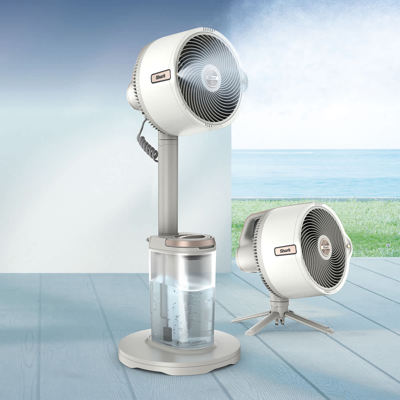 Two white misting fans—one pedestal with water tank and one tabletop—spraying mist on a seaside deck.