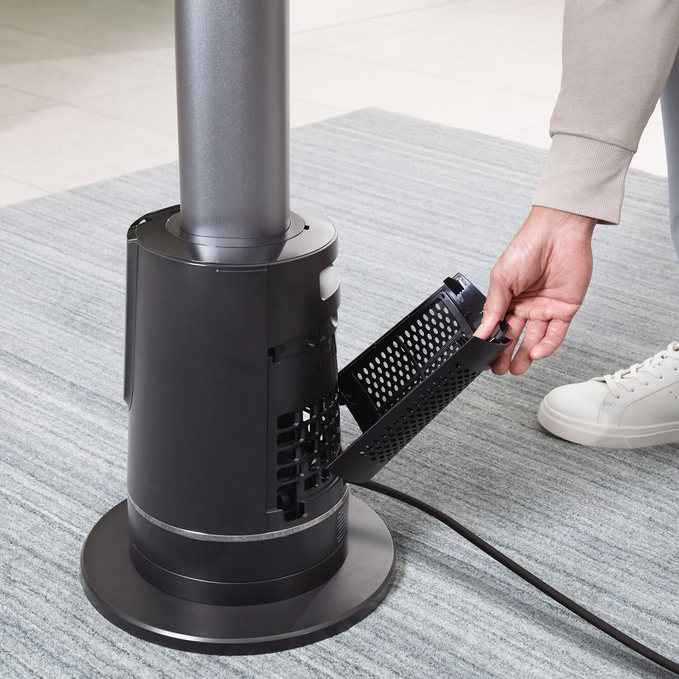 Close up of a person's hand removing the detachable Dust Defence filter from the base of a Shark Turbo Blade cool and heat fan