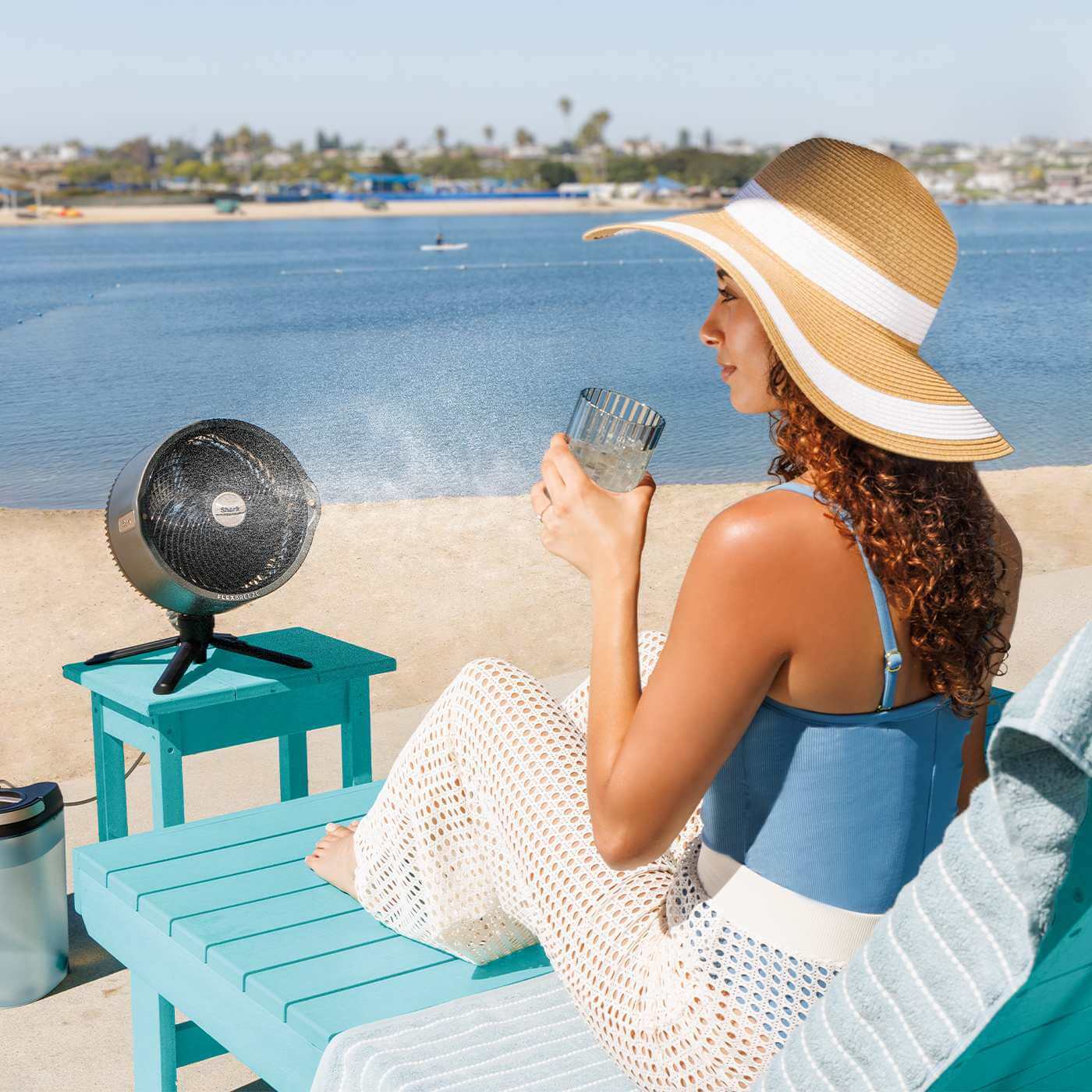 Image of woman sat on the beach with the shark misting fan